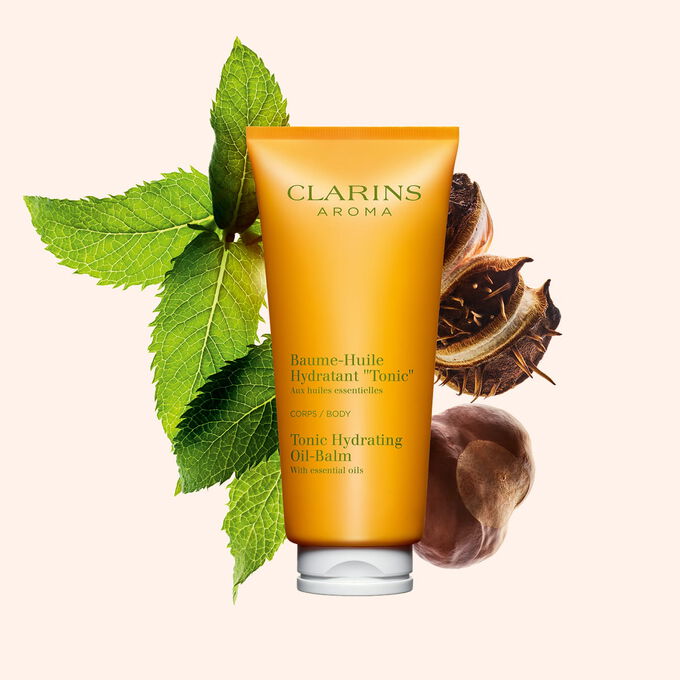 Packshot av en tub med Clarins Tonic Hydrating Oil-Balm, n&auml;ra n&aring;gra myntablad och shean&ouml;tter mot en persikof&auml;rgad bakgrund.