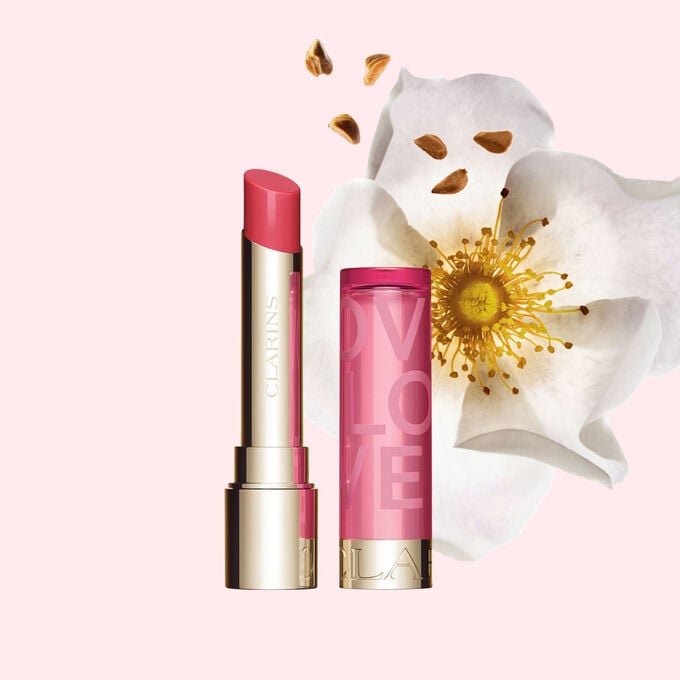 Packshot av Lip Balm Limited Edition Love Collection framf&ouml;r en ros p&aring; en ljusrosa bakgrund som framh&auml;ver den livfulla f&auml;rgen.