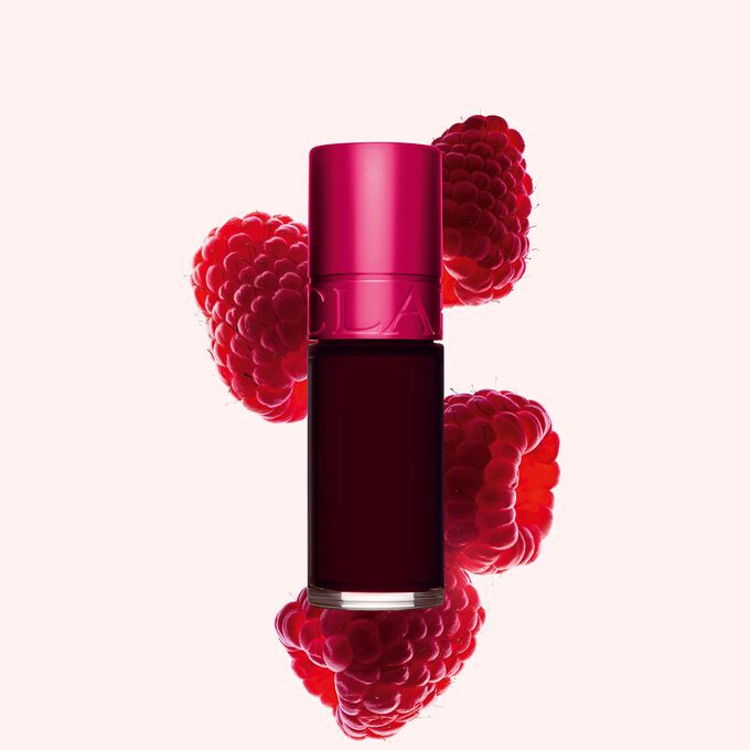 Packshot p&aring; Clarins Pink Water Lip Stain i nyansen 4, placerad bredvid hallon p&aring; en ljusrosa bakgrund