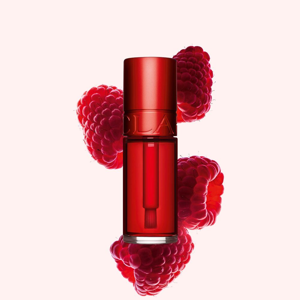 Packshot p&aring; Clarins Red Water Lip Stain i nyansen 03, placerad bredvid hallon p&aring; en ljusrosa bakgrund