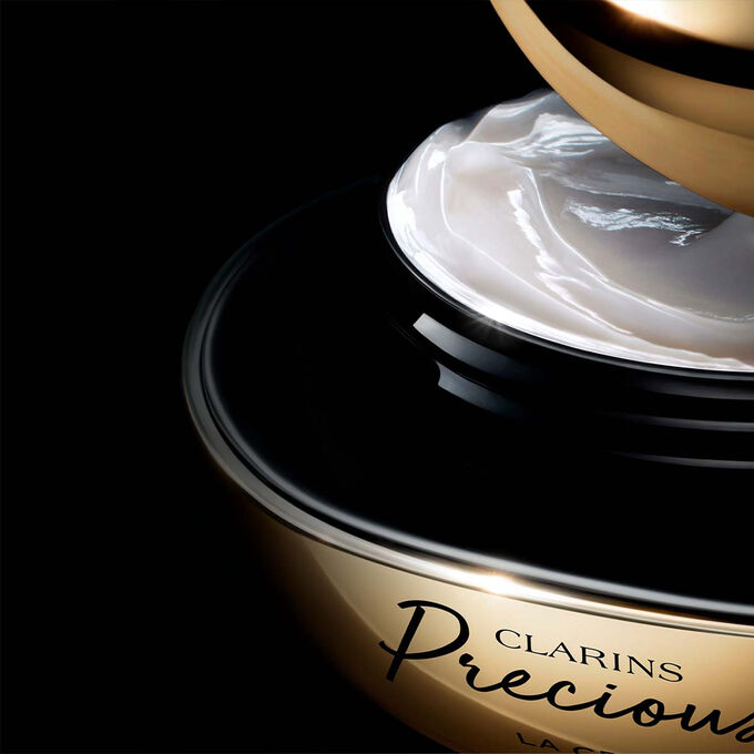 Packshot av Clarins Precious Soft Cream mot en m&ouml;rk bakgrund, med text som framh&auml;ver dess f&ouml;ryngrande effekt som f&aring;r huden att se fem &aring;r yngre ut