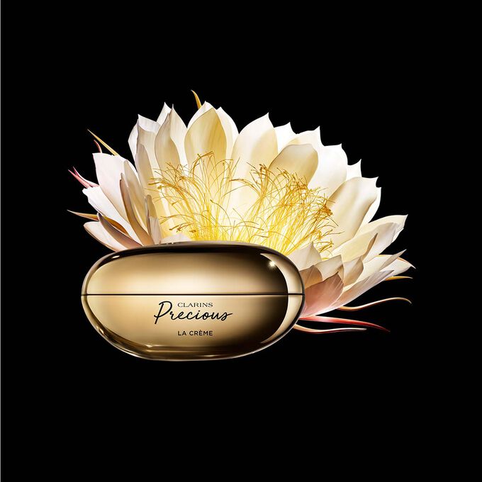 Packshot av Clarins Precious Soft Cream nära en blomma av nattens drottning mot en mörk bakgrund.