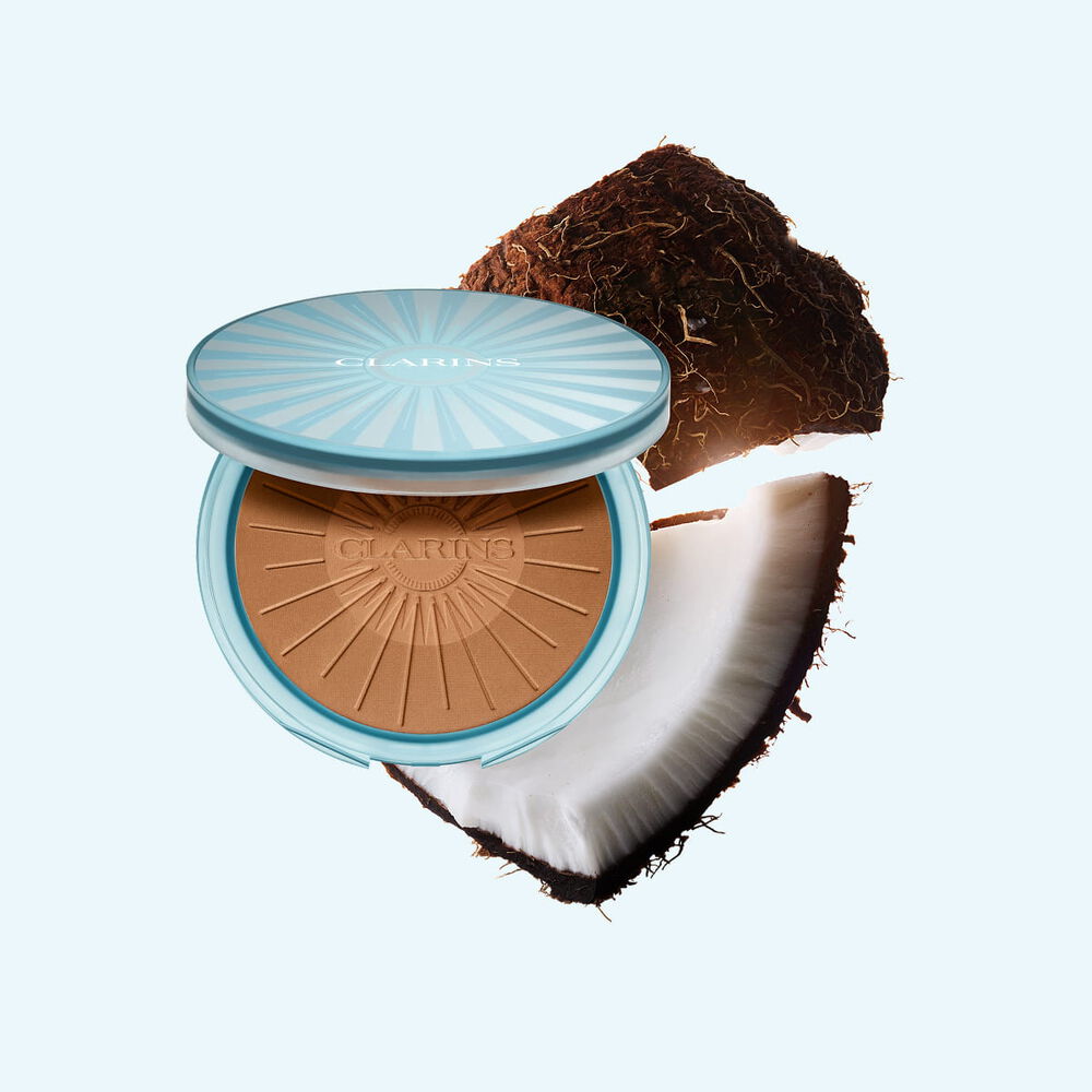 Packshot av Summer Bronzing Powder omgiven av kokos som illustrerar dess nyckelingrediens f&ouml;r en naturlig, solkysst lyster
