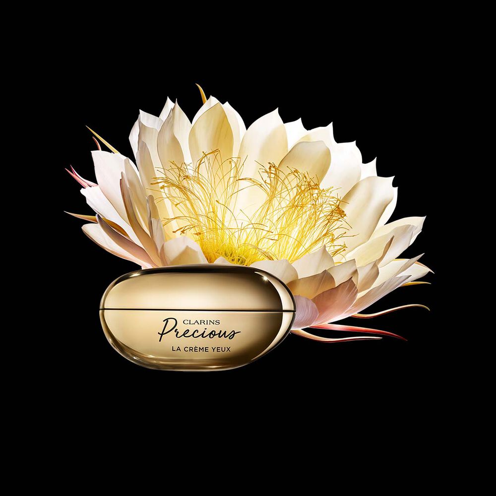 Packshot av ögonkrämen Clarins Precious Eyes nära en blomma av nattens drottning mot en mörk bakgrund.