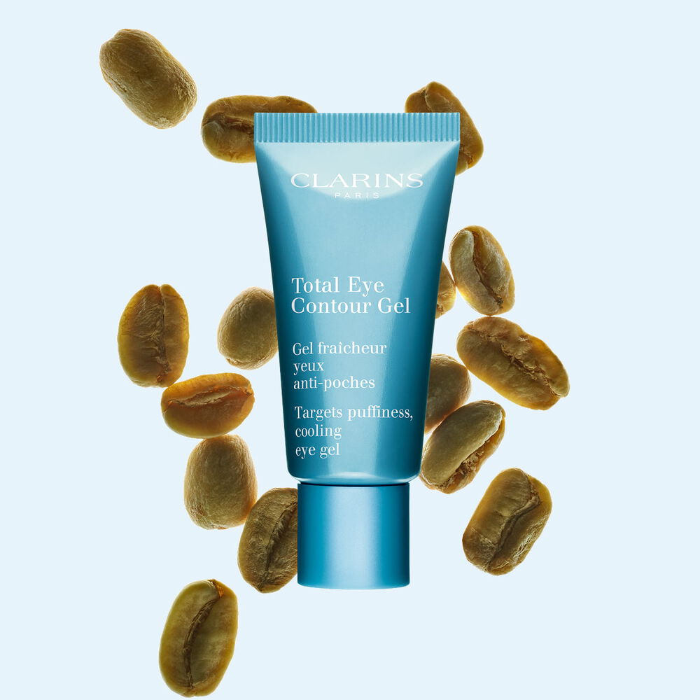 Packshot av en tub med Total Eye Contour Gel fr&aring;n Clarins, n&auml;ra kaffeb&ouml;nor mot en bl&aring; bakgrund.