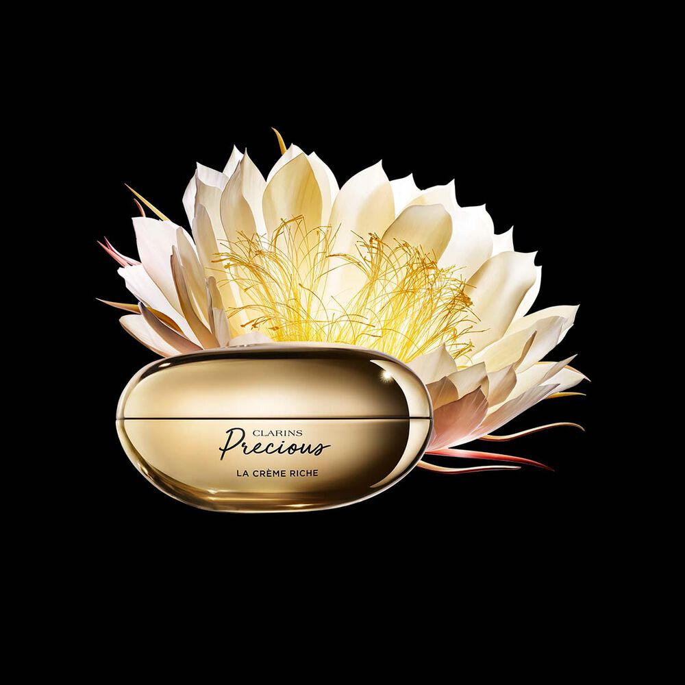 Packshot av Clarins Precious Rich Cream nära en blomma av nattens drottning mot en mörk bakgrund.