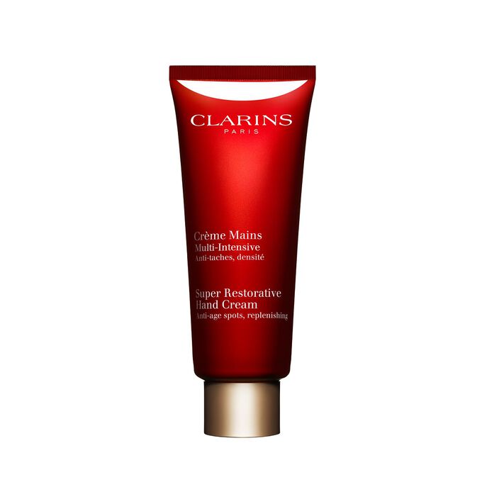 Packshot av en flaska med Clarins Super Restorative Hand Cream n&auml;ra n&aring;gra harunganablad mot en rosa bakgrund.