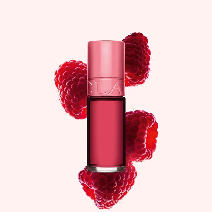 Packshot på Clarins Pink Water Lip Stain i nyansen 11, placerad bredvid hallon på en ljusrosa bakgrund
