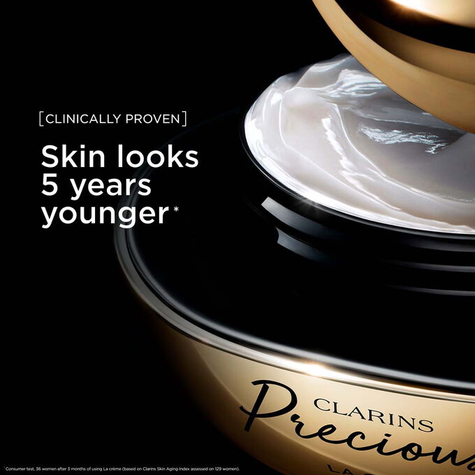 Packshot av Clarins Precious Soft Cream mot en m&ouml;rk bakgrund, med text som framh&auml;ver dess f&ouml;ryngrande effekt som f&aring;r huden att se fem &aring;r yngre ut