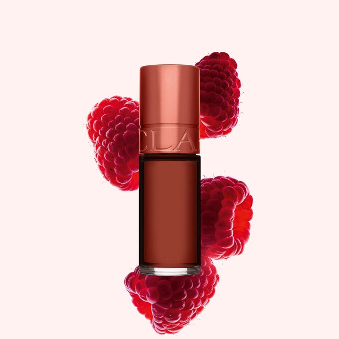 Packshot p&aring; Clarins Brown Water Lip Stain i nyansen 13, placerad bredvid hallon p&aring; en ljusrosa bakgrund
