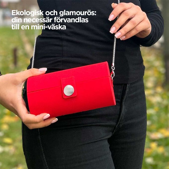 Närbild på necessären, som visar dess röda design och förmåga att förvandlas till en mini-väska med ett band.